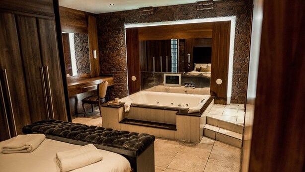 A modern bathroom with a large bathtub, a separate shower area, and a vanity with a mirror. - Infinity Apartments Victoria Street (Liverpool)