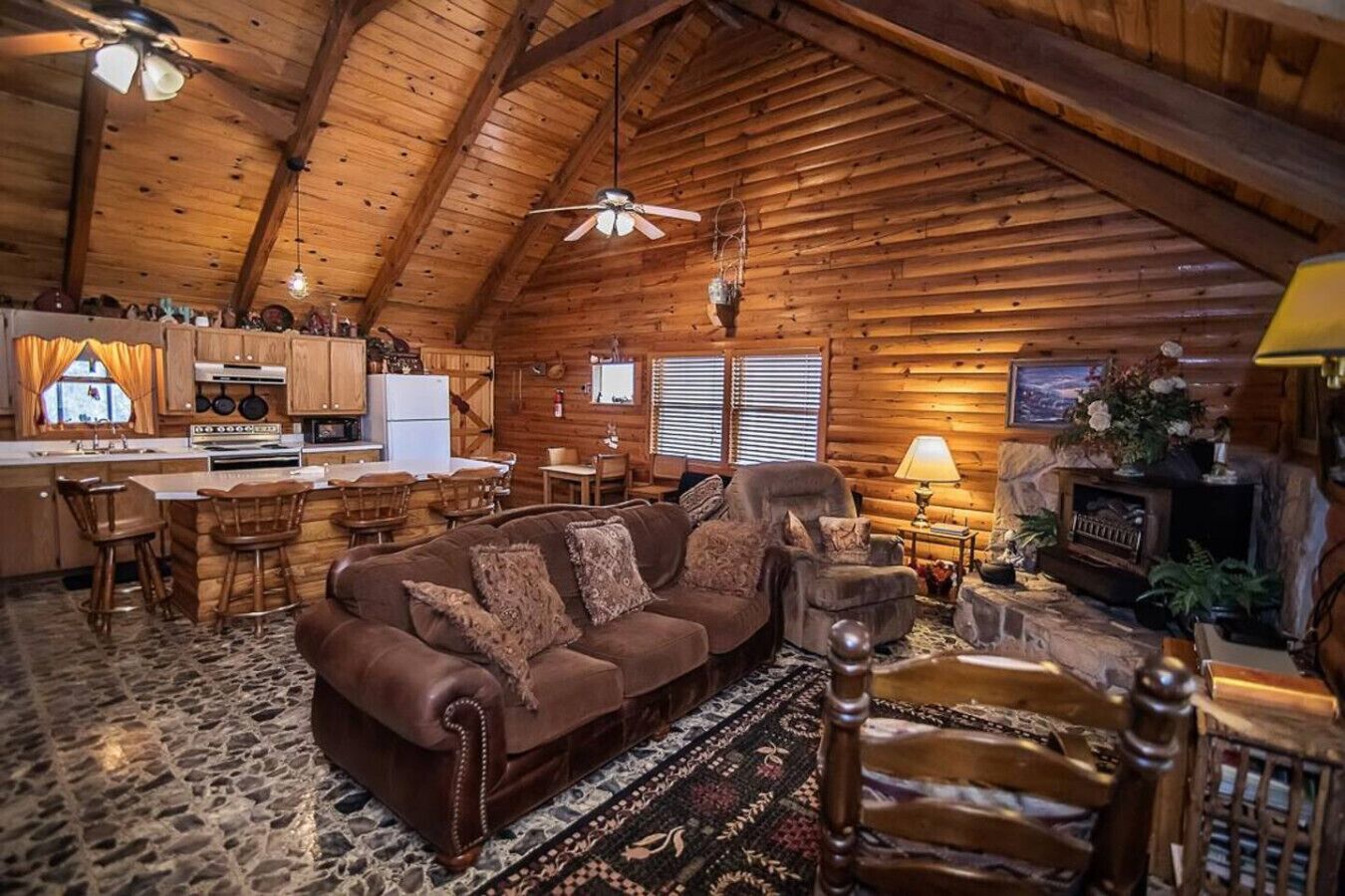 A log cabin interior with a living room, kitchen, and dining area.