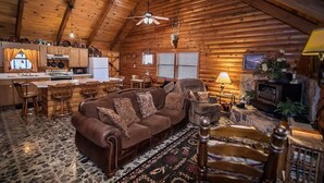 Interior de una cabaña de madera con sala de estar, cocina y comedor.