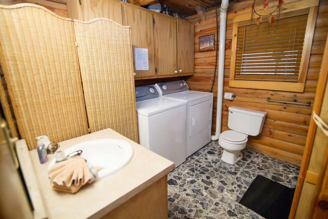 Une petite salle de bain équipée d’un lave-linge, de toilettes et d’un lavabo.