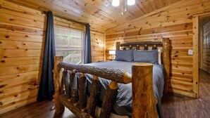 Een houten slaapkamer met een bed, een plafondventilator en een raam met gordijnen.