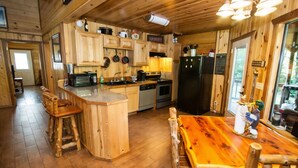 A rustic kitchen with wooden cabinets, a central island, and a dining table.