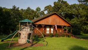 A rustic cabin with a wooden exterior, a porch, and an American flag.