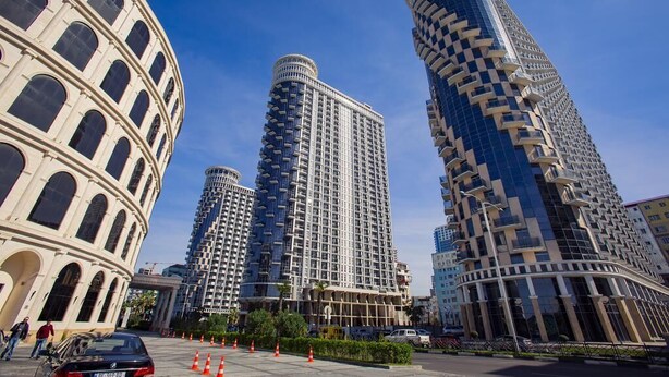 A modern urban area with a prominent historical building and three high-rise buildings with unique architectural designs. - Golden Apartments (Batumi)