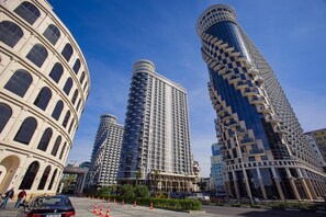 A modern urban area with a prominent historical building and three high-rise buildings with unique architectural designs. - Golden Apartments (Batumi)