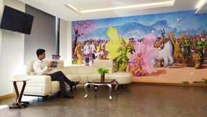 A modern lobby with a large mural, a flat-screen TV, and a seating area with a coffee table.