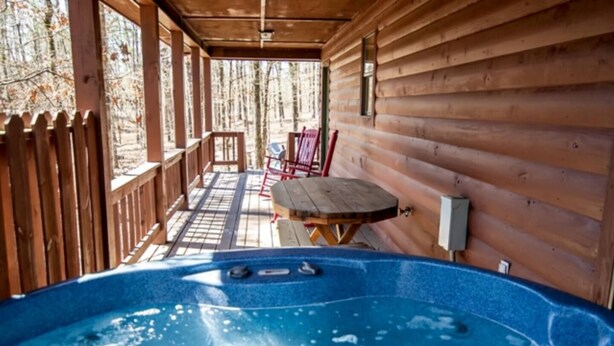 Una baita di legno con idromassaggio, un tavolo e sedie all'esterno.
