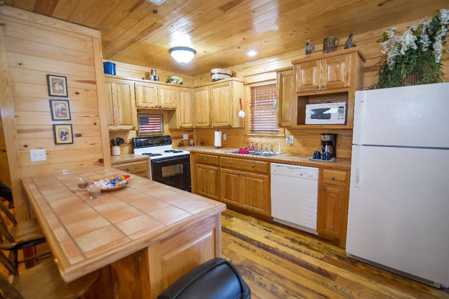 A wooden cabin-style kitchen with a stove, sink, and refrigerator.