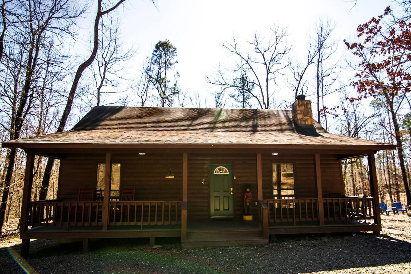 A rustic cabin with a porch, a chimney, and a door with a decorative arch.