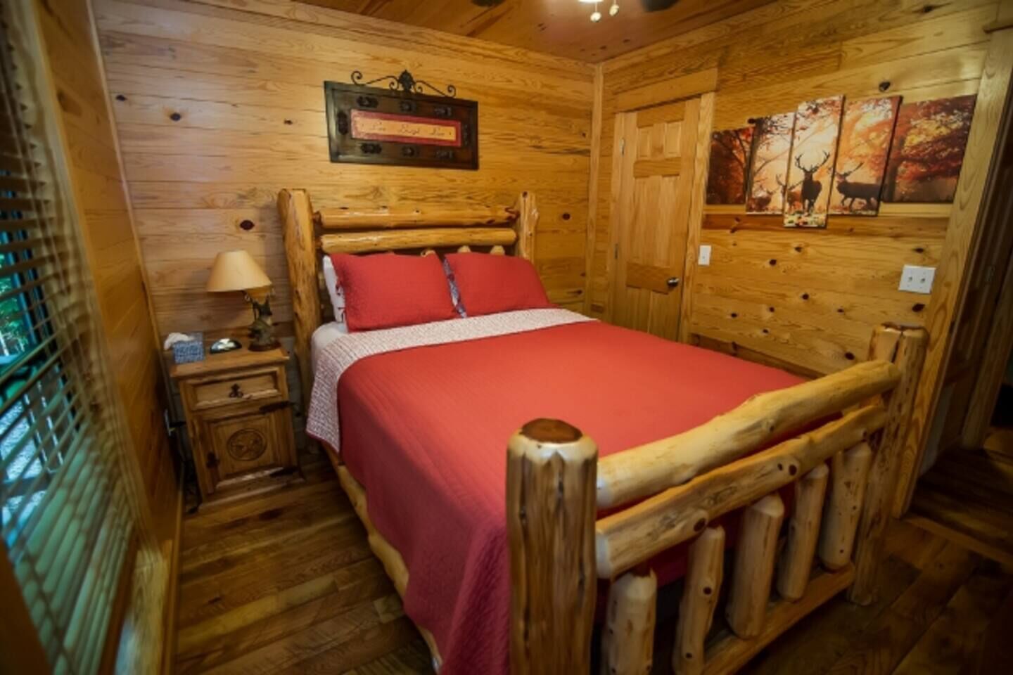 Una habitación de madera con una cama, una mesita de noche, una lámpara y un cuadro en la pared.