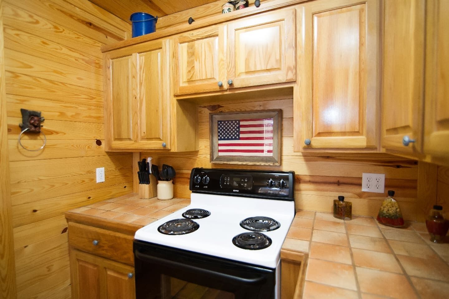 Una cocina con armarios de madera, una estufa blanca y una decoración con la bandera estadounidense.