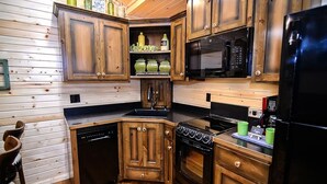 Una cocina compacta con armarios de madera, lavavajillas, estufa y microondas.