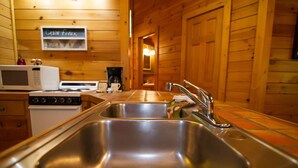 A kitchen with stainless steel sinks, a microwave, and a stove. - Papa Bear- Broken Bow/Hochatown- 1bd (Broken Bow)