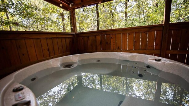 A hot tub with a wooden deck and a view of trees. - Cozy Hochatown Cabin w/ Private Hot Tub (Broken Bow)