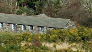 A stone house with a sloped roof, surrounded by dense shrubbery and trees. - The perfect place to take a step back from it all (Renvyle)