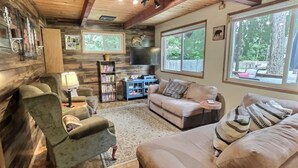 Una sala acogedora con sofá, sillones, una mesa de centro, una estantería y televisor.