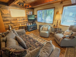 A cozy living room with a sofa, armchairs, a television, and a wooden wall. - Papa`s Packwood Cabin (Packwood)