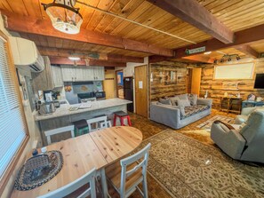 A cozy cabin interior with a dining area, kitchen, and seating space.