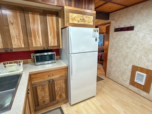 A compact kitchen with wooden cabinets, a stainless steel microwave, and a white refrigerator. - Culps Cascade | Wi-Fi, Woodstove, Cedar Hot tub (Packwood)