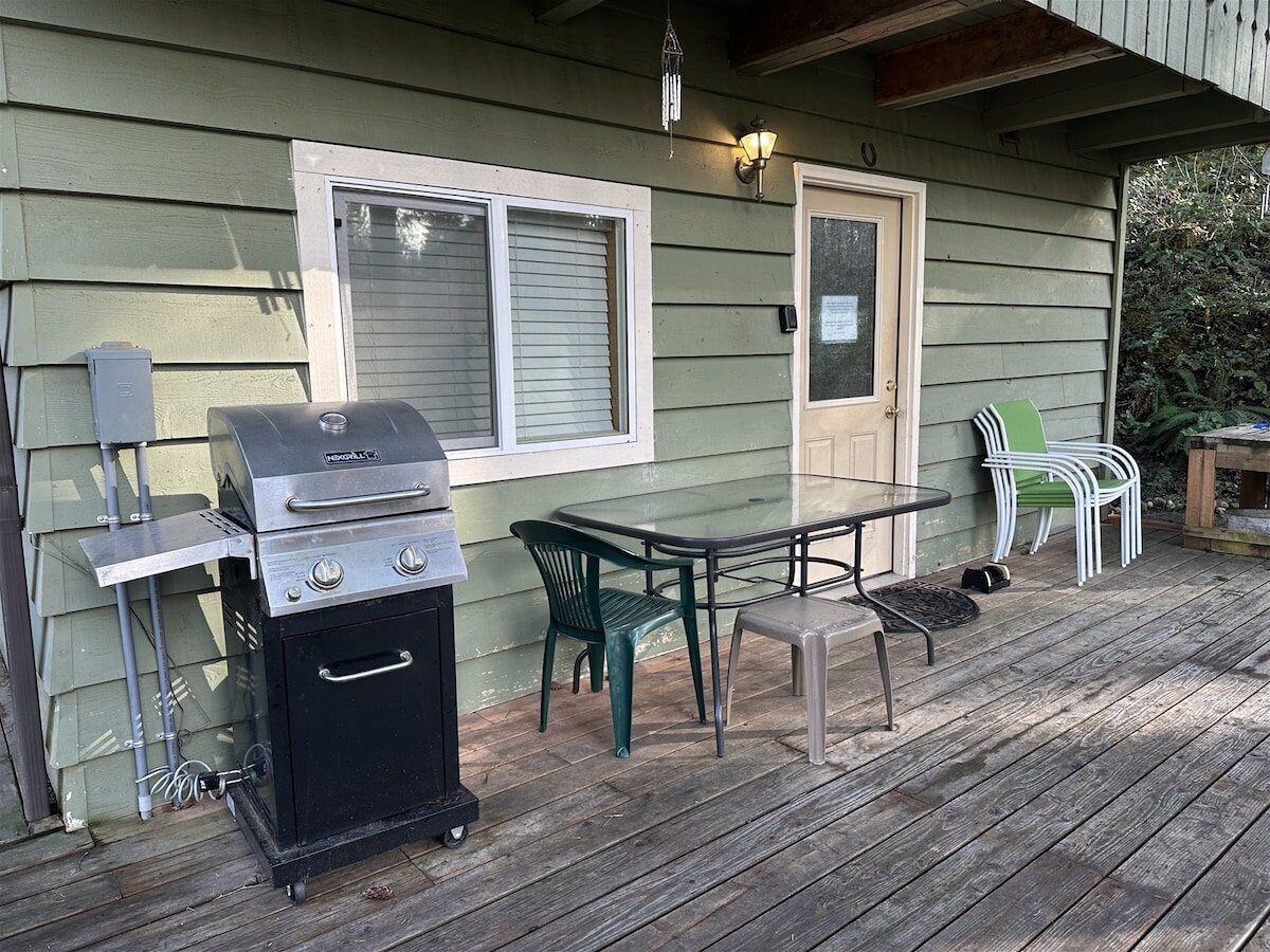Eine Terrassengruppe mit Grill, Tisch und Stühlen.