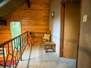 L’intérieur d’un chalet en bois, avec un escalier, une petite table, une chaise et une porte.