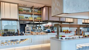 A modern kitchen with a central island, various kitchen appliances, and a chef preparing food. - Hilton Garden Inn Kuwait (Kuwait City)