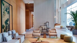 A spacious lobby with a modern design, featuring a sofa set, armchairs, a coffee table, and a large potted plant. - Hilton Garden Inn Kuwait (Kuwait City)