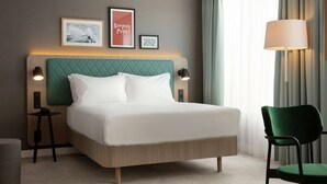 Habitación de hotel ordenada con cama, mesitas de noche, una silla y una lámpara.