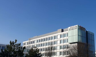 A modern building with a glass facade and a sign reading "Hilton Garden Inn."