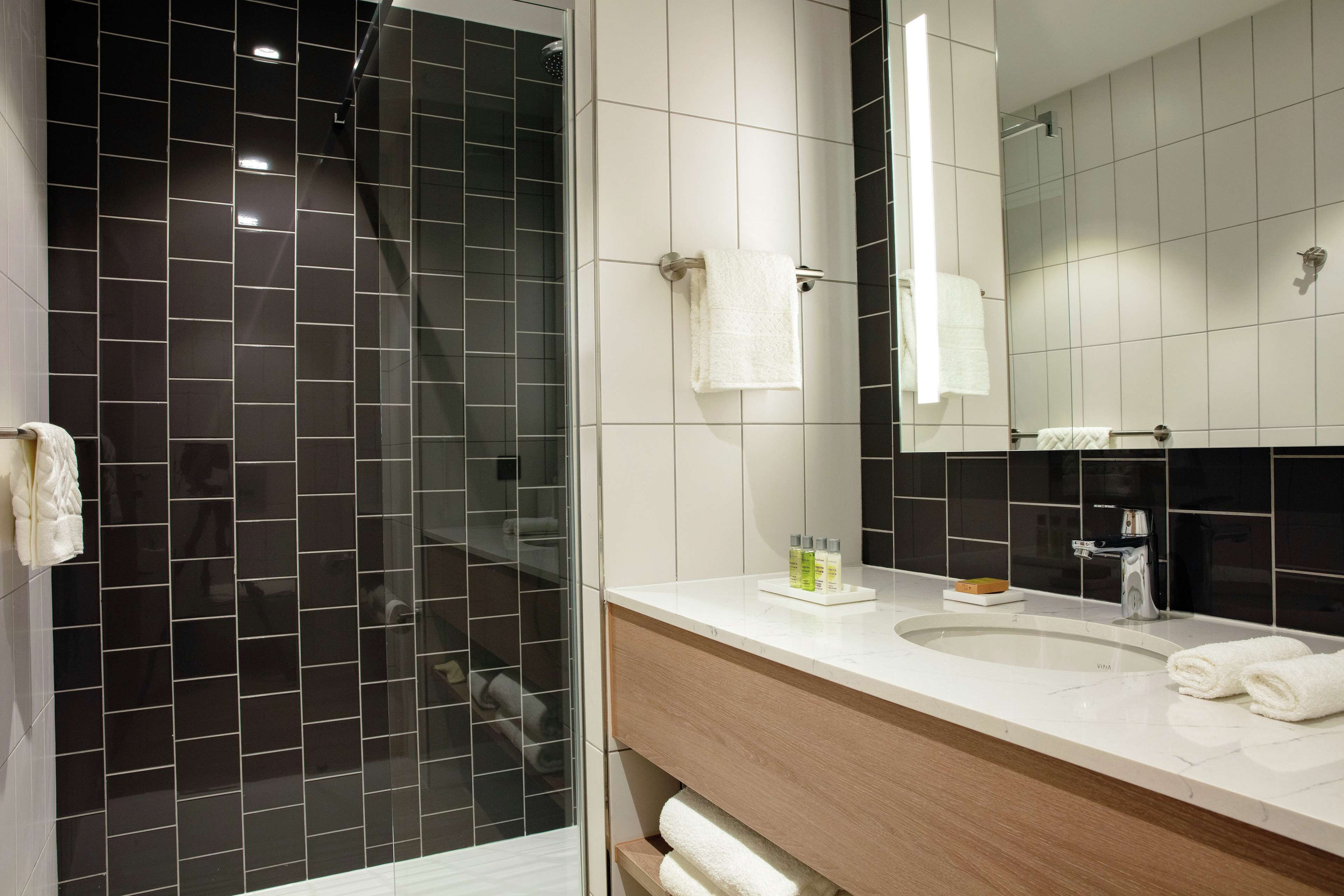 A modern bathroom with a glass-enclosed shower, a white sink, and a mirror above it.