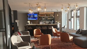 Una sala de estar moderna con un área de bar, asientos cómodos y ventanas amplias.