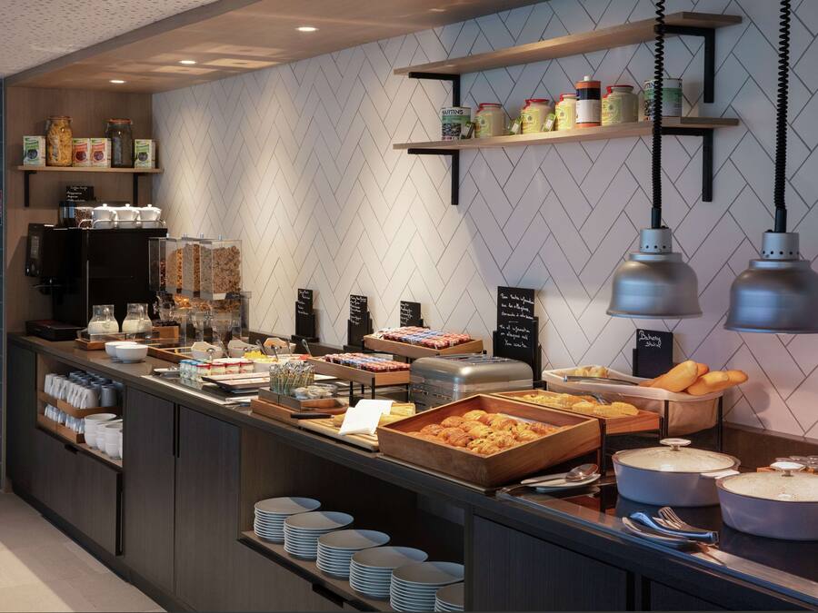 A buffet area with various food items, serving trays, and condiment containers.