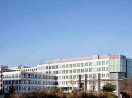Un hotel moderno con techo plano, varios pisos y un llamativo letrero de Hilton Garden Inn.