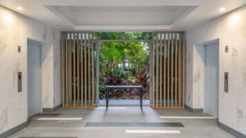 A modern hallway with marble walls, a wooden gate, and a view of an outdoor garden.
