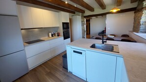 Une cuisine moderne avec des armoires blanches, un lave-vaisselle intégré et un mur décoratif en pierre.