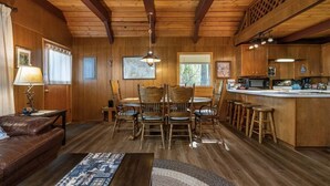 Un acogedor interior de cabaña con comedor, cocina y zona de estar.