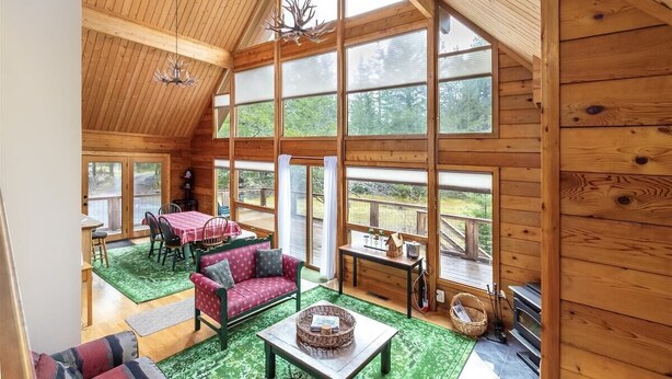A spacious cabin with a high ceiling, large windows, a dining area, and a cozy seating area. - Trails End | Hot Tub, Starlink, Woodstove (Packwood)