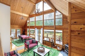 A spacious cabin with a high ceiling, large windows, a dining area, and a cozy seating area. - Trails End | Hot Tub, Starlink, Woodstove (Packwood)