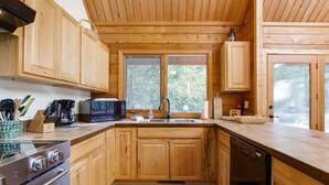 A wooden cabin kitchen with a stove, microwave, sink, and wooden cabinets. - Trails End | Hot Tub, Starlink, Woodstove (Packwood)