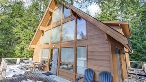 A wooden cabin with large windows, a deck, and outdoor seating. - Trails End | Hot Tub, Starlink, Woodstove (Packwood)