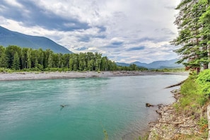 A river with clear turquoise water, surrounded by dense green forest and mountains in the background. - Twin Maples | River Access, BBQ (Packwood)