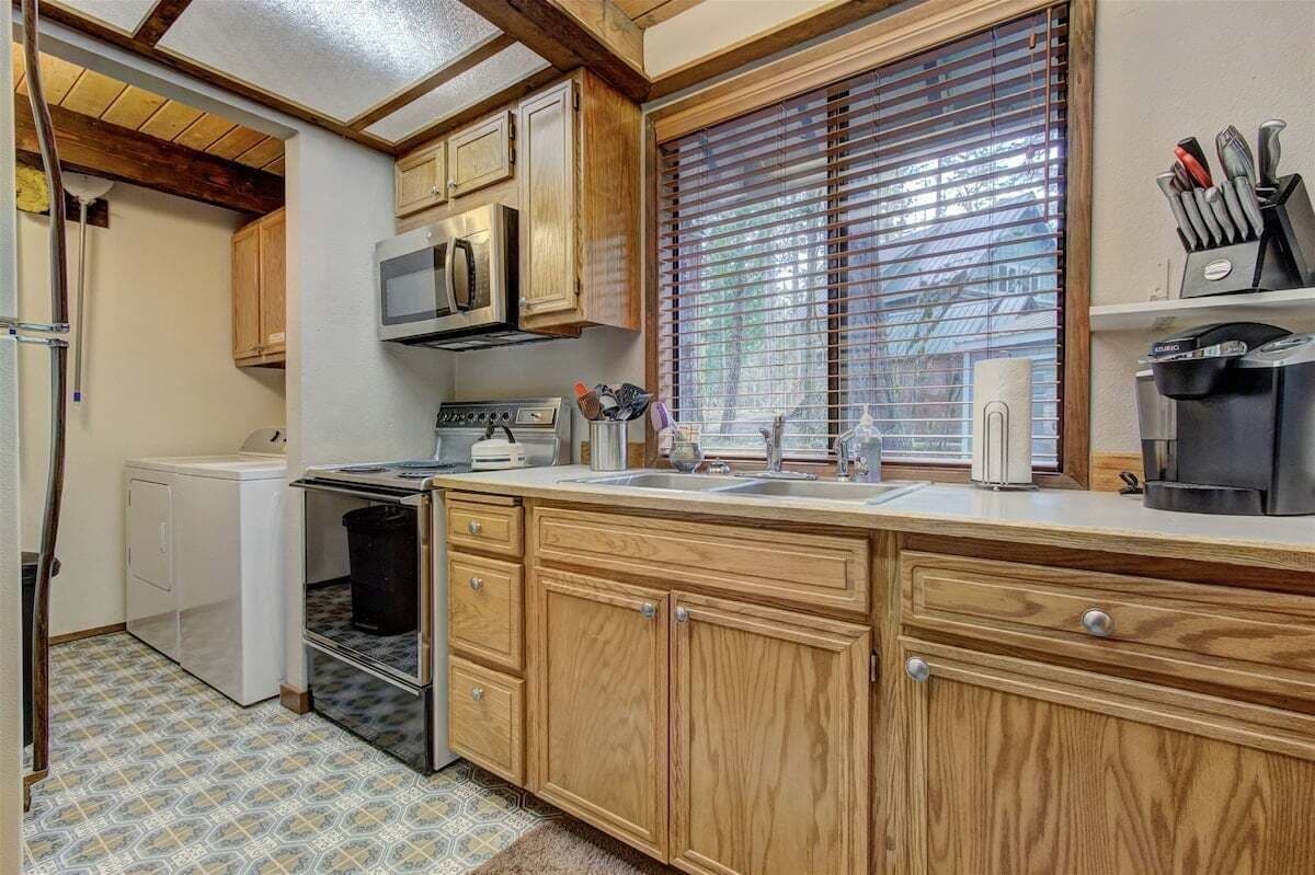 A compact kitchen with wooden cabinets, a microwave, a stove, and a coffee maker.