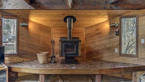 A rustic wooden cabin with a central wood-burning stove, a mounted deer skull, and a woven basket on a bench. - Lake Creek Retreat| Mt Rainier, WiFi, Woodstove (Packwood)