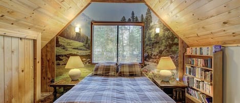 Un dormitorio acogedor en el ático con una cama grande, dos lámparas de noche, una estantería y una vista panorámica por la ventana.