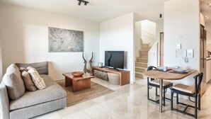 Un salon moderne comprenant un canapé, une table basse, un téléviseur et un coin repas avec des chaises et une table.