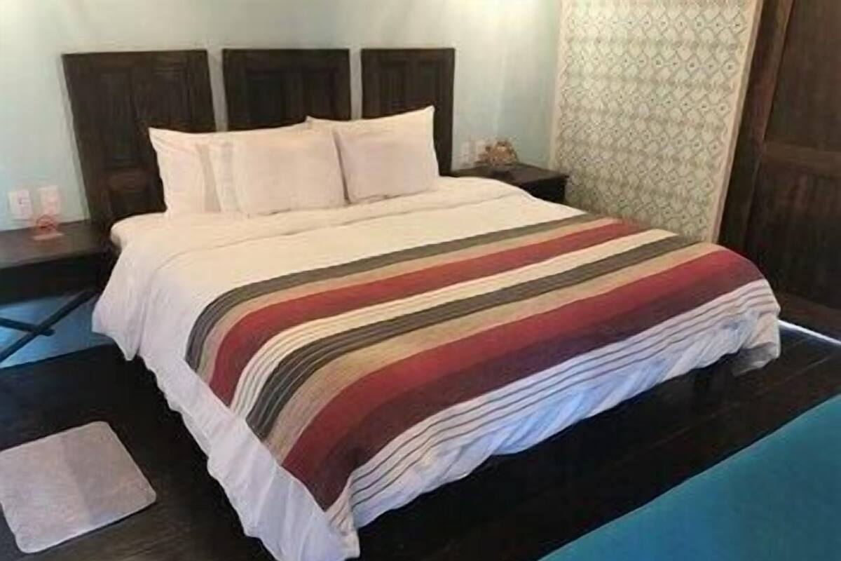 A bed with a striped bedspread, a bedside table, and a nightstand.