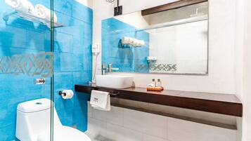 Un baño con inodoro, lavamanos y cabina de ducha de vidrio.