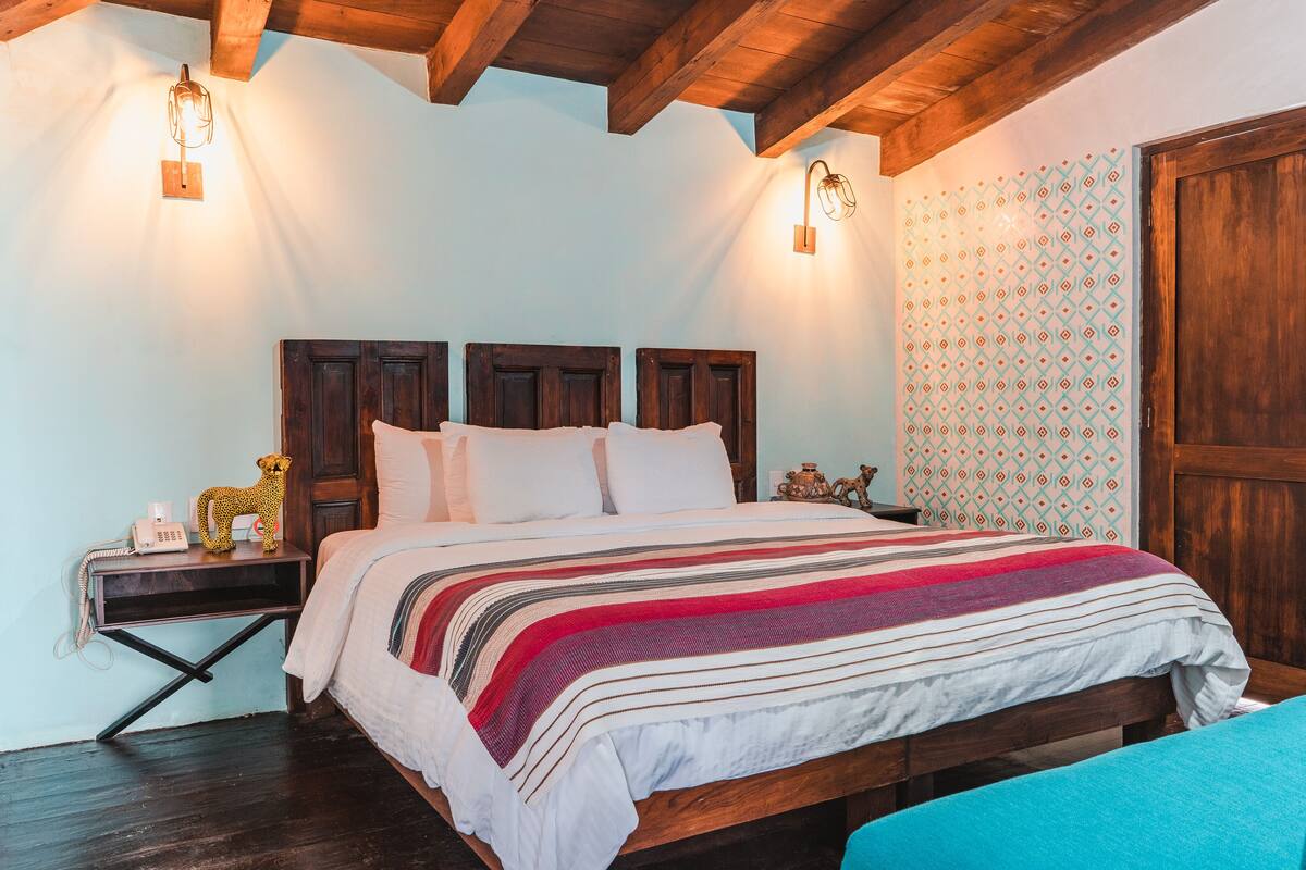 A bedroom with a wooden bed, a nightstand, and a patterned wall.