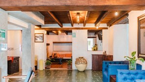A lobby with a wooden ceiling, a large vase, blue sofas, and a fireplace. - Yox Hotel Boutique (San Cristóbal de las Casas)