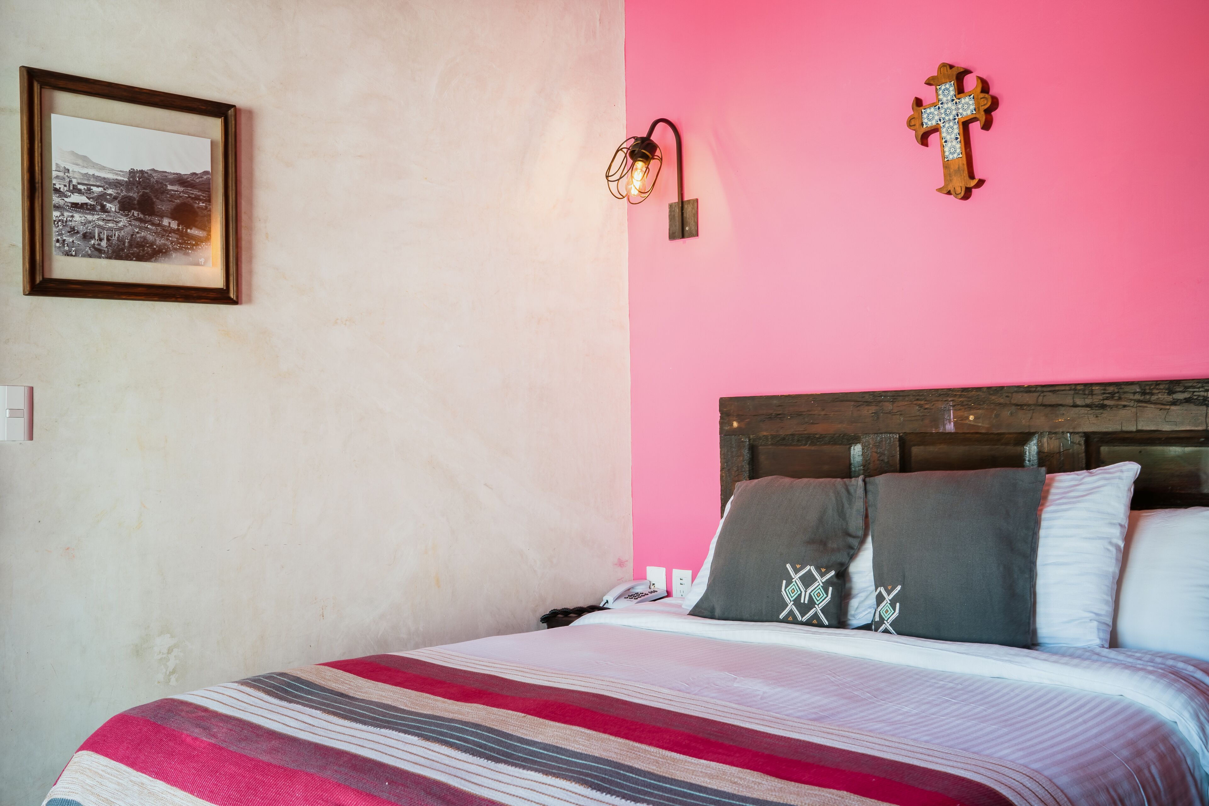 A bed with a striped blanket, a wooden headboard, and two pillows with geometric patterns.